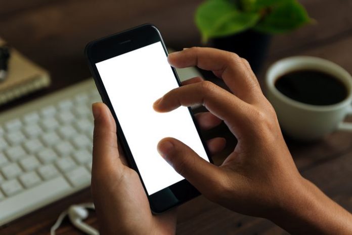 closeup hand use phone showing white screen on work desk, blank